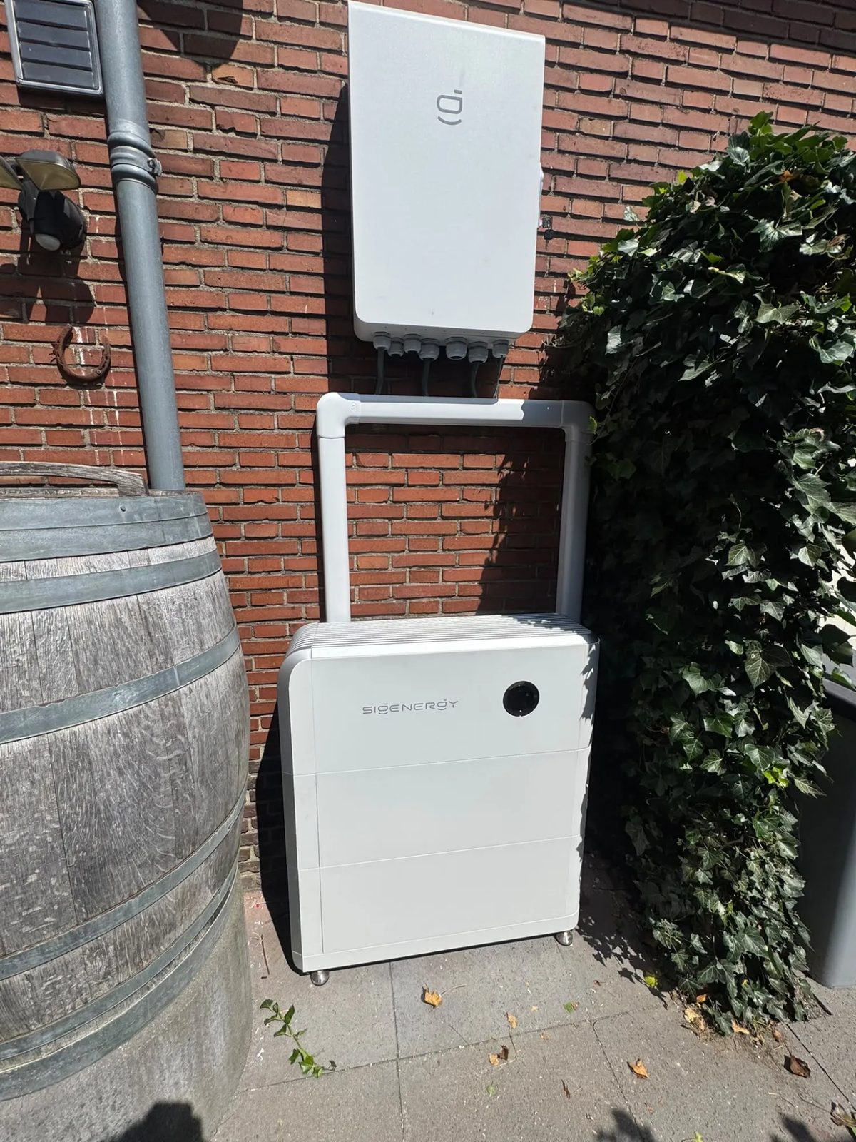 Sigenergy-thuisbatterij met omvormer aan een bakstenen gevel